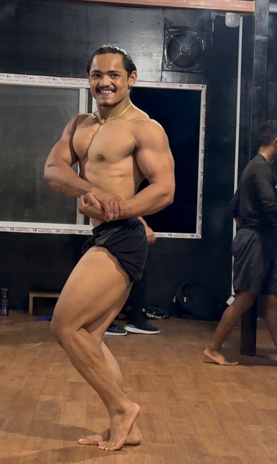 Body Workshop member posing on stage at a bodybuilding competition